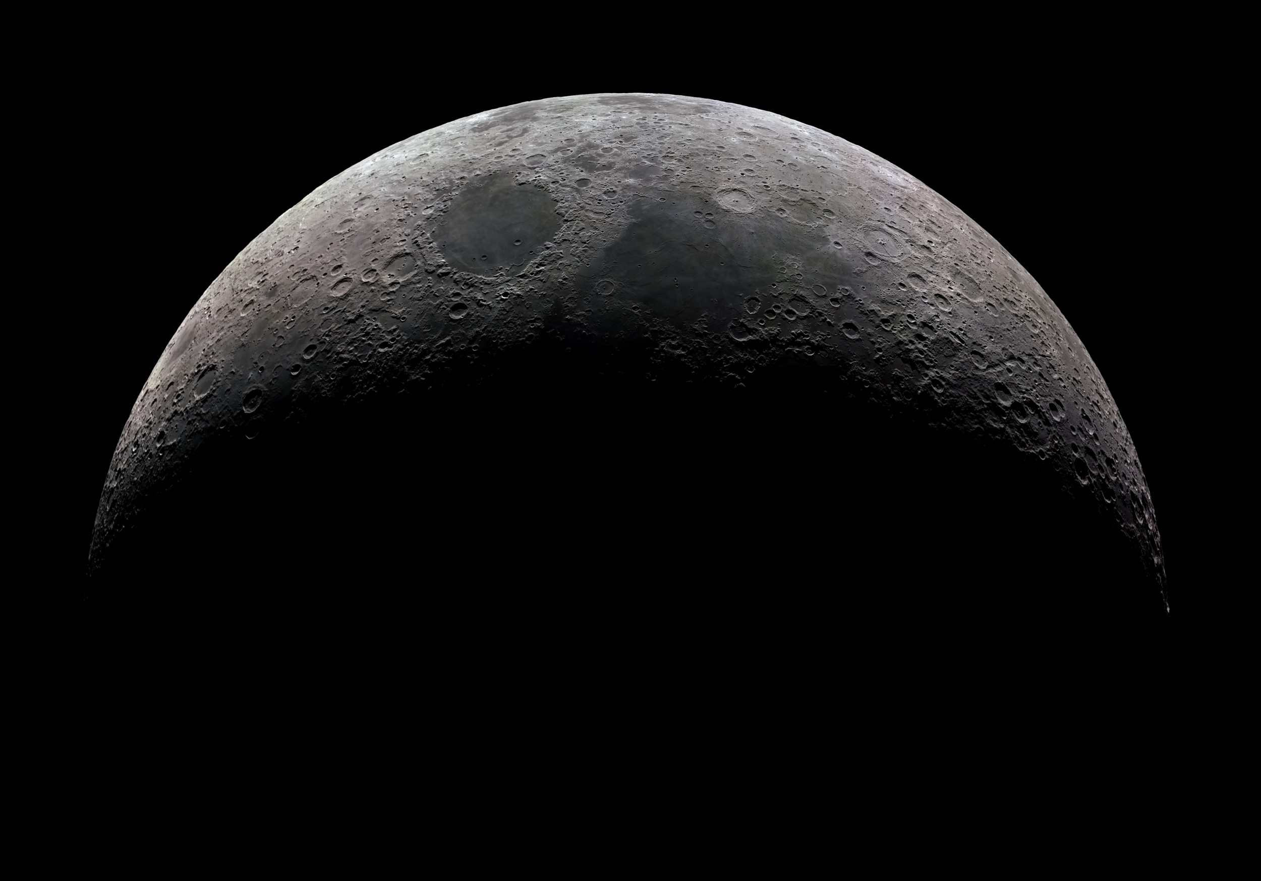 A detailed view of the Moon’s surface shows craters and rough terrain, with the lower half in shadow and the upper half illuminated against a black background.